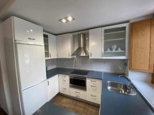 a kitchen with white appliances and a blue counter top at Camino del Norte vivienda turística ubicada en Pobeña in Poveña