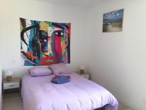 a bedroom with a bed with a painting on the wall at L'abbevilloise, aux portes de la Baie de Somme in Abbeville