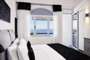 um quarto com uma cama e uma janela grande em Mr and Mrs White Oia - Santorini em Oia