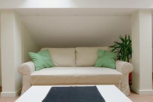 a white couch with two green pillows on it at VUKAJLO apartment Belgrade in Belgrade