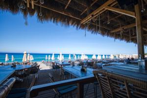 a beach with tables and umbrellas and the ocean at Island Boutique Hotel in Rhodes Town