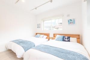 two twin beds in a room with white walls at West Coast Villa Shirahama in Shirahama