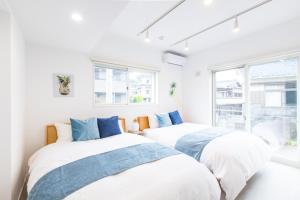 2 Betten in einem weißen Zimmer mit Fenstern in der Unterkunft West Coast Villa Shirahama in Shirahama
