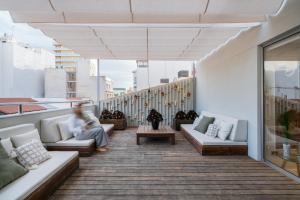 a woman sitting on a balcony with couches and tables at Hospes Amérigo, Alicante, a Member of Design Hotels in Alicante