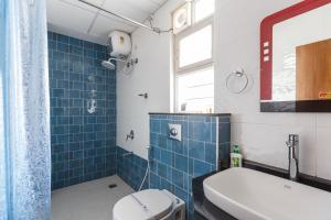 a bathroom with a toilet and a blue tiled shower at BluO Studio Koramangala - Terrace Garden, Parking in Bengaluru