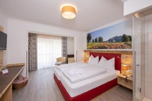 a bedroom with a large bed with a painting on the wall at Genusshotel Almrausch in Bad Kleinkirchheim