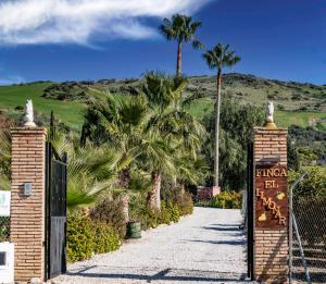 een poort naar een villa met palmbomen bij Finca El Limonar in Alora