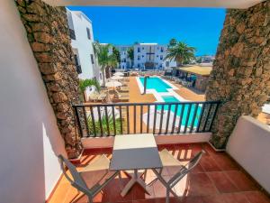 balcón con mesa y sillas y piscina en Club Atlántico, en Puerto del Carmen