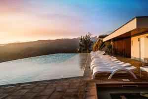 uma piscina com espreguiçadeiras brancas ao lado de um edifício em Pousadela Village & Spa em Vieira do Minho