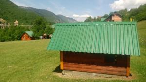 a small building with a green roof on a field at Kamp Rafting Kljajevića Luka in Pljevlja
