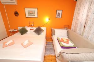 two twin beds in a room with orange walls at Guest House Jungher in Korčula
