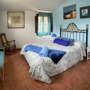 1 dormitorio con 1 cama grande con almohadas azules en Casa rural Cal Fuster Experience, en Terrades