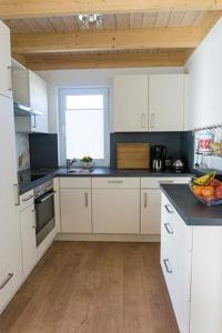 a kitchen with white cabinets and a bowl of fruit on the counter at Ferienhaus Sonnenufer in Rheinsberg