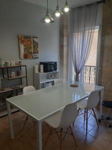 una mesa y sillas blancas en una habitación con ventana en Maison de ville dans une citée médiévale, en Gourdon-en-quercy