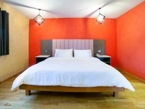 a bedroom with a large bed with an orange wall at Hotel Casona de Minas in Mineral del Monte