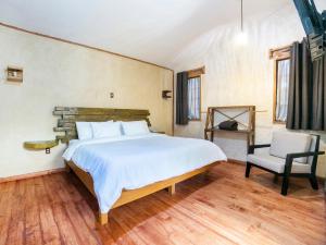 a bedroom with a large bed and a chair at Hotel Casona de Minas in Mineral del Monte