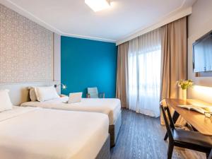 um quarto de hotel com duas camas e uma secretária em Mercure Florianópolis em Florianópolis