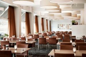 - une salle à manger avec des tables, des chaises et de grandes fenêtres dans l'établissement Comwell Rebild Bakker, à Skorping