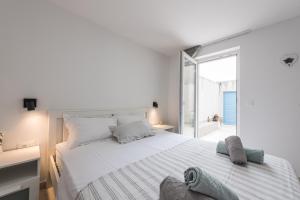 a white bedroom with a large bed and a window at Apartman Festini in Pag