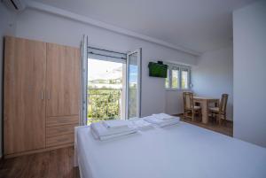 - une chambre avec un lit blanc, une table et une fenêtre dans l'établissement Apartman Arijana, à Trebinje