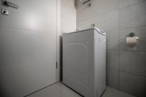 La salle de bains est pourvue de toilettes blanches et d'un distributeur de papier toilette. dans l'établissement Apartman Arijana, à Trebinje