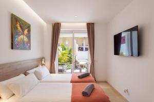 Villa Deluxe Suites Maspalomas في ماسبالوماس: غرفه فندقيه سريرين وتلفزيون
