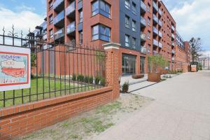 a brick building with a fence in front of it at Gdansk Old Town Walowa Apartments by Renters in Gdańsk
