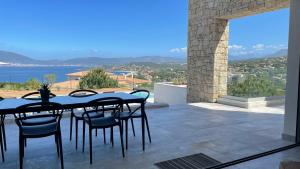 een tafel en stoelen op een patio met uitzicht bij LES VILLAS DU DOMAINE NAPOLEON CORSICA vue mer et piscine in Pietrosella