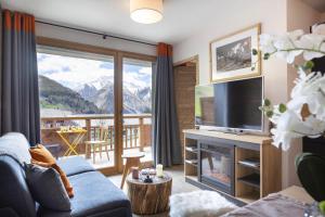 een woonkamer met een bank, een televisie en een balkon bij Résidence Club MMV Les Clarines in Les Deux Alpes