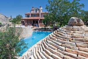 a retaining wall next to a swimming pool with a house at Holiday House Cukrići in Cukrići
