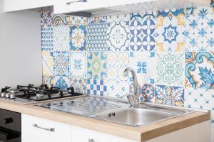 a kitchen with a sink and tiles on the wall at GLBapartments in Capo dʼOrlando