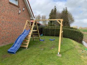 ein Spielplatz mit Rutsche und Schaukel in der Unterkunft 50059 Ferienhaus in Altfunnixsiel
