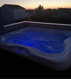 uma grande banheira cheia de água azul à noite em Central Apartment with Jacuzzi em Novalja