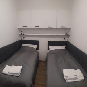 two beds in a small room with white cabinets at Apartament Kąty Rybackie Zaciszna in Kąty Rybackie