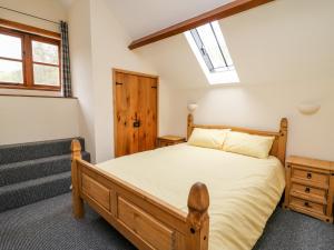 a bedroom with a wooden bed and a skylight at Ploony Barn in Bleddfa