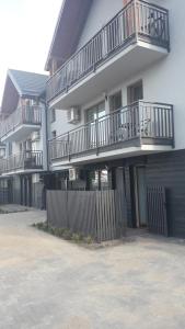 a building with balconies and a fence in front of it at Apartament Kąty Rybackie Zaciszna in Kąty Rybackie