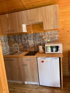 a small kitchen with a microwave and a refrigerator at Domki letniskowe i pokoje Miedzywodzie in Międzywodzie