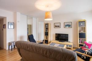 een woonkamer met een bank en een tv bij Le Sainte Anne in Saint-Malo