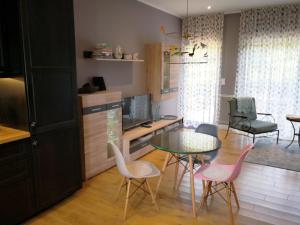 uma cozinha com uma mesa de vidro e cadeiras cor-de-rosa em La Normandise em Cormeilles