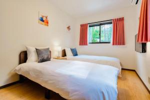 two beds in a room with red curtains at Sali's House in Hakuba