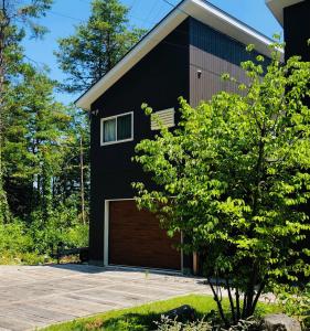 una casa negra con garaje de madera en Sali's House en Hakuba