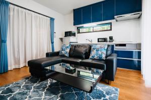 a living room with a black leather couch and blue cabinets at Sali's House in Hakuba