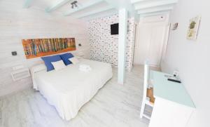 een slaapkamer met een wit bed en blauwe kussens bij Hotel La Torre in Tarifa