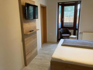 1 dormitorio con 1 cama y TV en la pared en Nordseehotel Eymers, en Nordholz