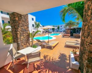 a patio with chairs and a swimming pool with palm trees at Club Atlántico in Puerto del Carmen