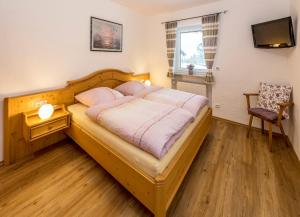 Un dormitorio con una gran cama de madera con sábanas rosas. en Ferienwohnung Schnitzlbaumer, en Bischofswiesen