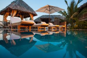 a resort swimming pool with chairs and an umbrella at Villa Del Sol in Máncora