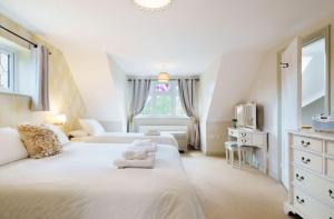 a white bedroom with two beds and a tv at Grove Lodge in Gosport
