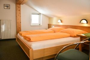 ein Schlafzimmer mit einem großen Bett mit orangefarbener Bettwäsche in der Unterkunft Haus Alpenblick in Schröcken
