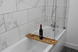 a bottle of wine and two glasses on a tray in a bath tub at Newly Refurbished 3 Bed 2.5 Bath House in Staines in Staines